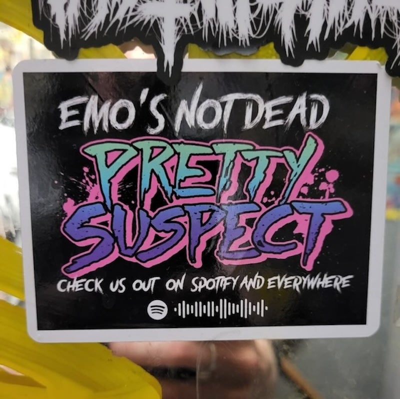 Picture of a black sign that says "Emo's not dead, Pretty Suspect, check us out on spotify and everywhere" and a spotify url code.