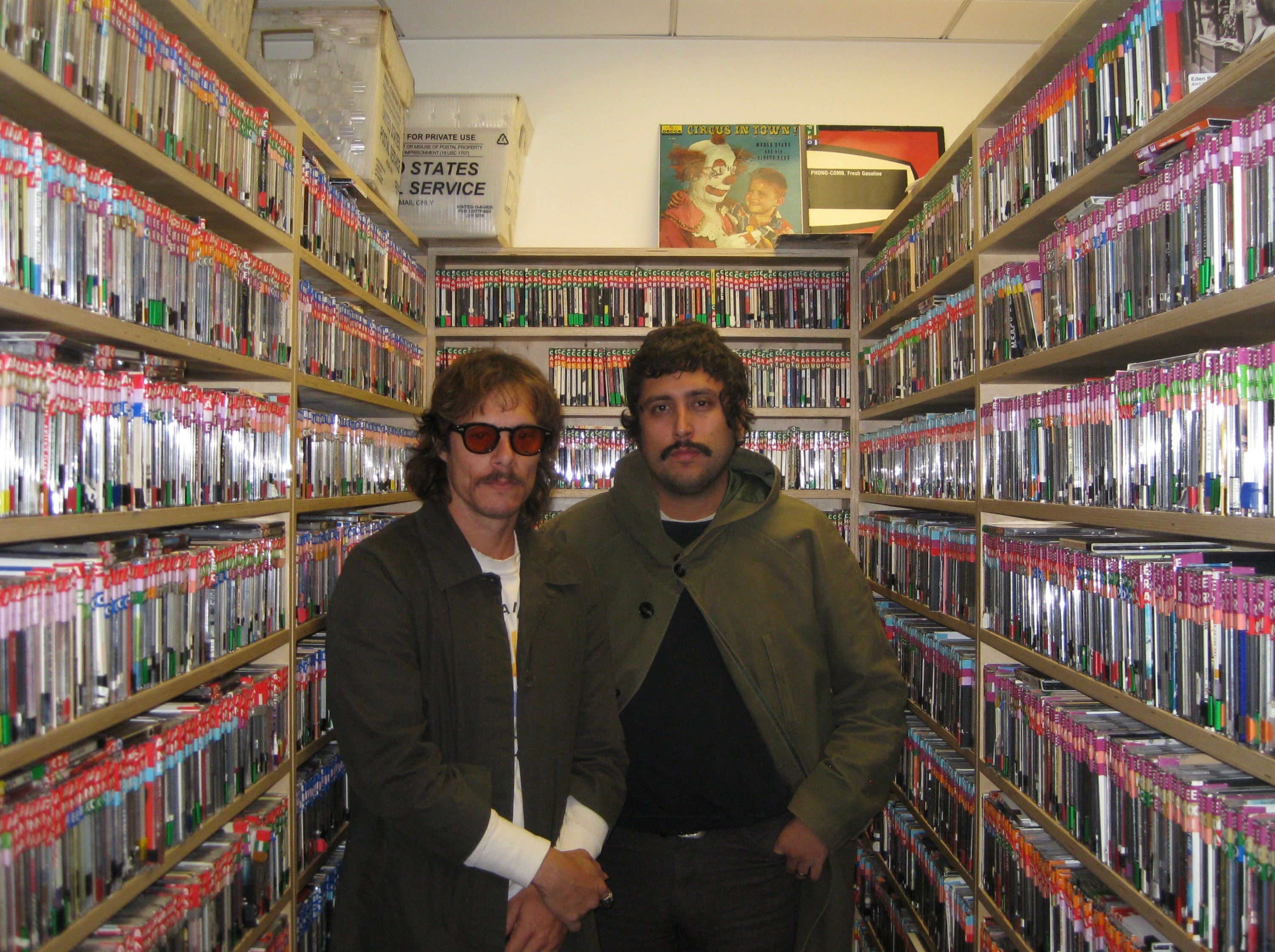 2 members of the windows band standing in the room of KWVA that holds all the CDs and records. 