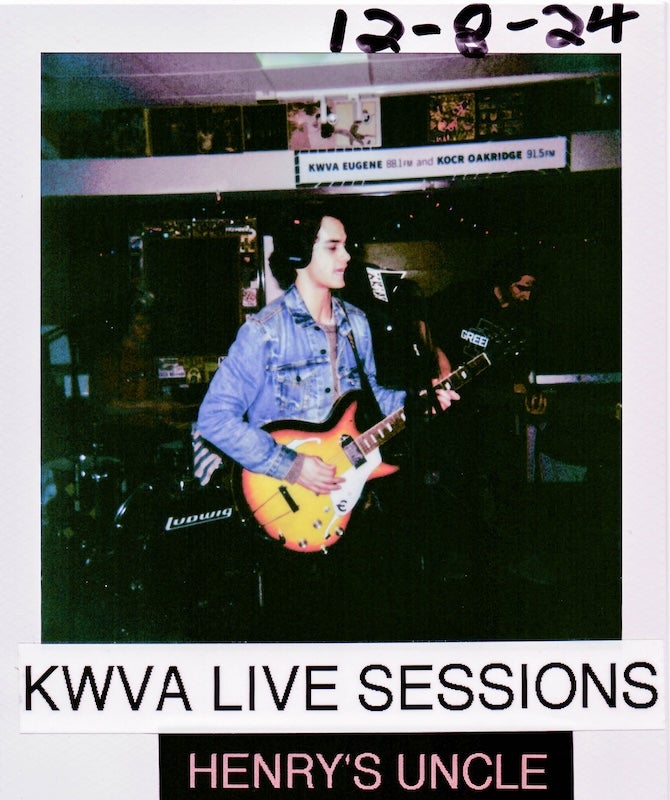 Polaroid photo reading "KWVA LIVE SESSIONS HENRY'S UNCLE 12-8-24" with young white man with black hair and denim jacket holding guitar singing into microphone