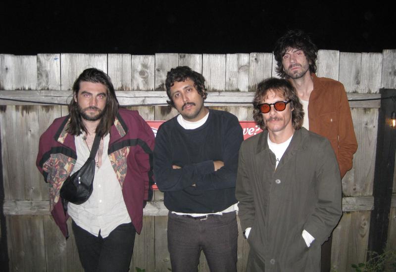 4 men posing in front a fence, they are the band members fr the band Windows.