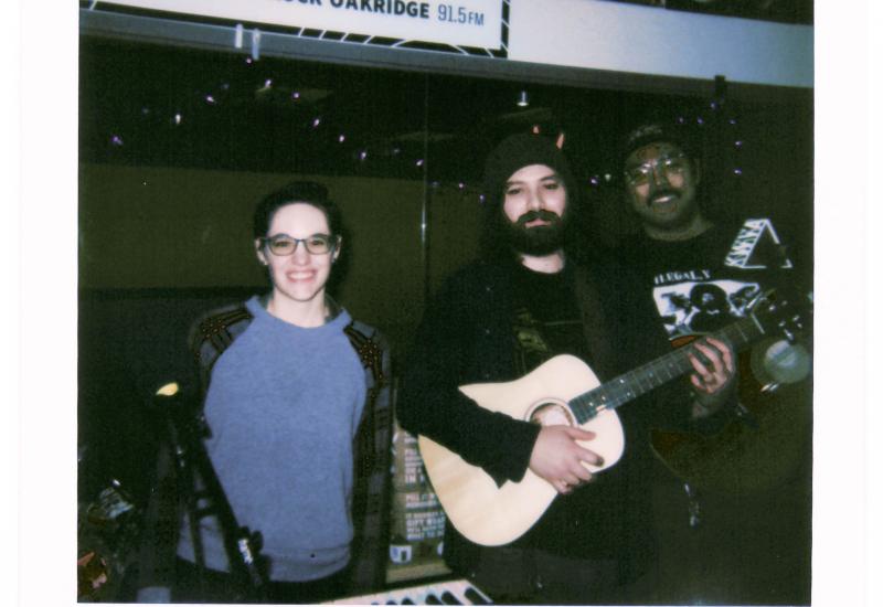 Polaroid photo reading "KWVA LIVE SESSIONS BABY GRENDEL 12-15-24" with 3 people posing together